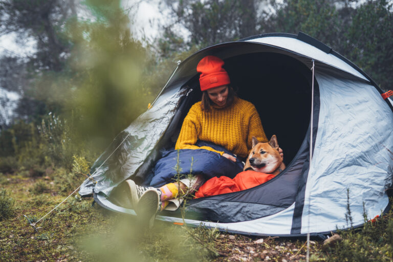 Frau mit Hund beim Camping